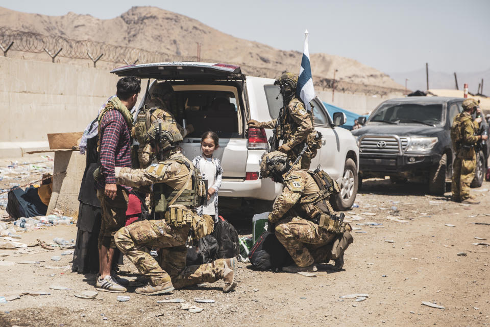 In this image provided by the U.S. Marine Corps, Finnish coalition forces assist evacuees for onward processing during an evacuation at Hamid Karzai International Airport in Kabul, Afghanistan, on Tuesday, Aug. 24, 2021. As the U.S. rushes to evacuate Americans and allies from Afghanistan, a growing number of Republicans are questioning why the U.S. should take in Afghan citizens who worked side by side with Americans. (Staff Sgt. Victor Mancilla/U.S. Marine Corps via AP)