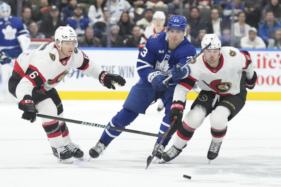 Toronto Maple Leafs' Matthew Knies, center, battles for the puck with Ottawa Senators' Jakob Chychrun, left, and Josh Norris during the second period of an NHL hockey match in Toronto, on Wednesday, Nov. 8, 2023. (Chris Young/The Canadian Press via AP)
