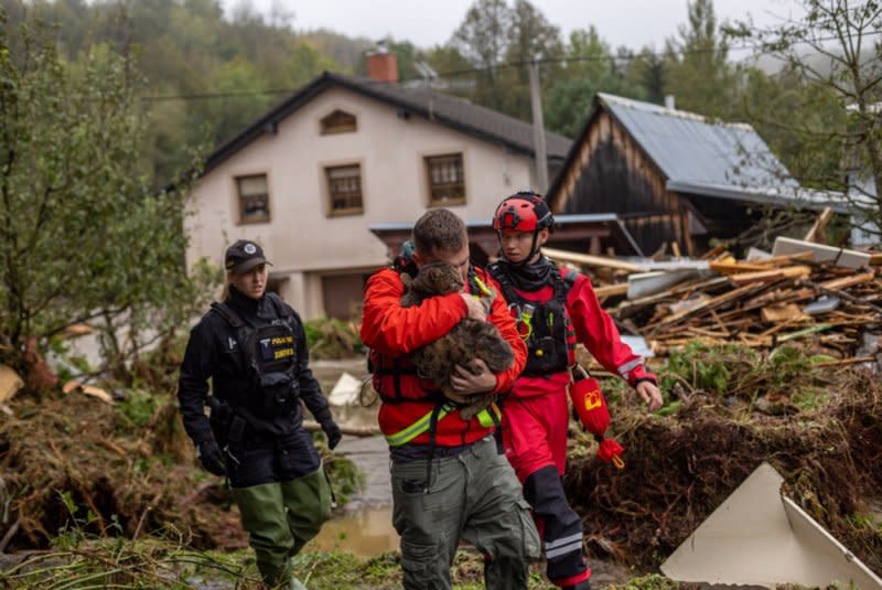 A local man (C) carries his cat on Sunday after he was evacuated from a house in the overflowing Bela river after heavy rain in town of Jesenik, Czech Republic. Rain is expected to continue in parts of Europe through mid-week. Photo Provided by Martin Divisek/EPA-EFE