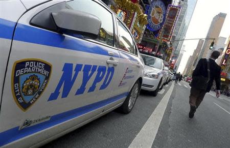 A pedestrian walks past a line of New York Police Department (NYPD) cars parked at Times Square in New York, October 18, 2011. REUTERS/Gary Hershorn