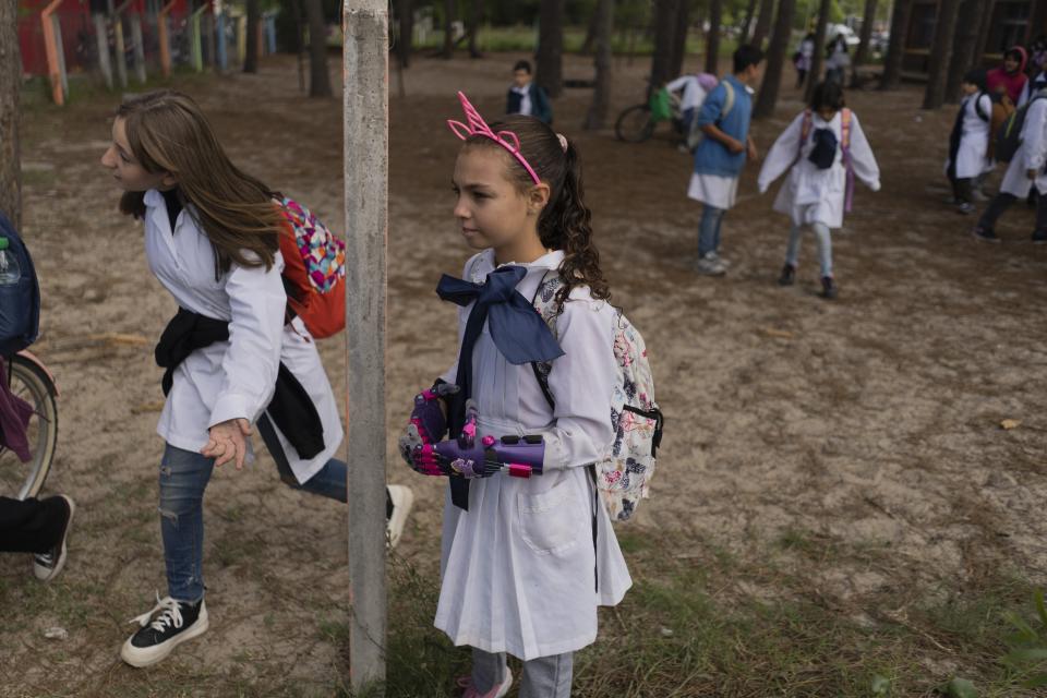 Mía Rodríguez, al frente, espera para entrar a su escuela en Salinas, Uruguay, el viernes 14 de abril de 2023. Mía recibió sus prótesis de manos de la fundación Manos de Héroes, que las diseña e imprime en 3D tanto para niños como para adultos en Uruguay. (AP Foto/Matilde Campodónico)