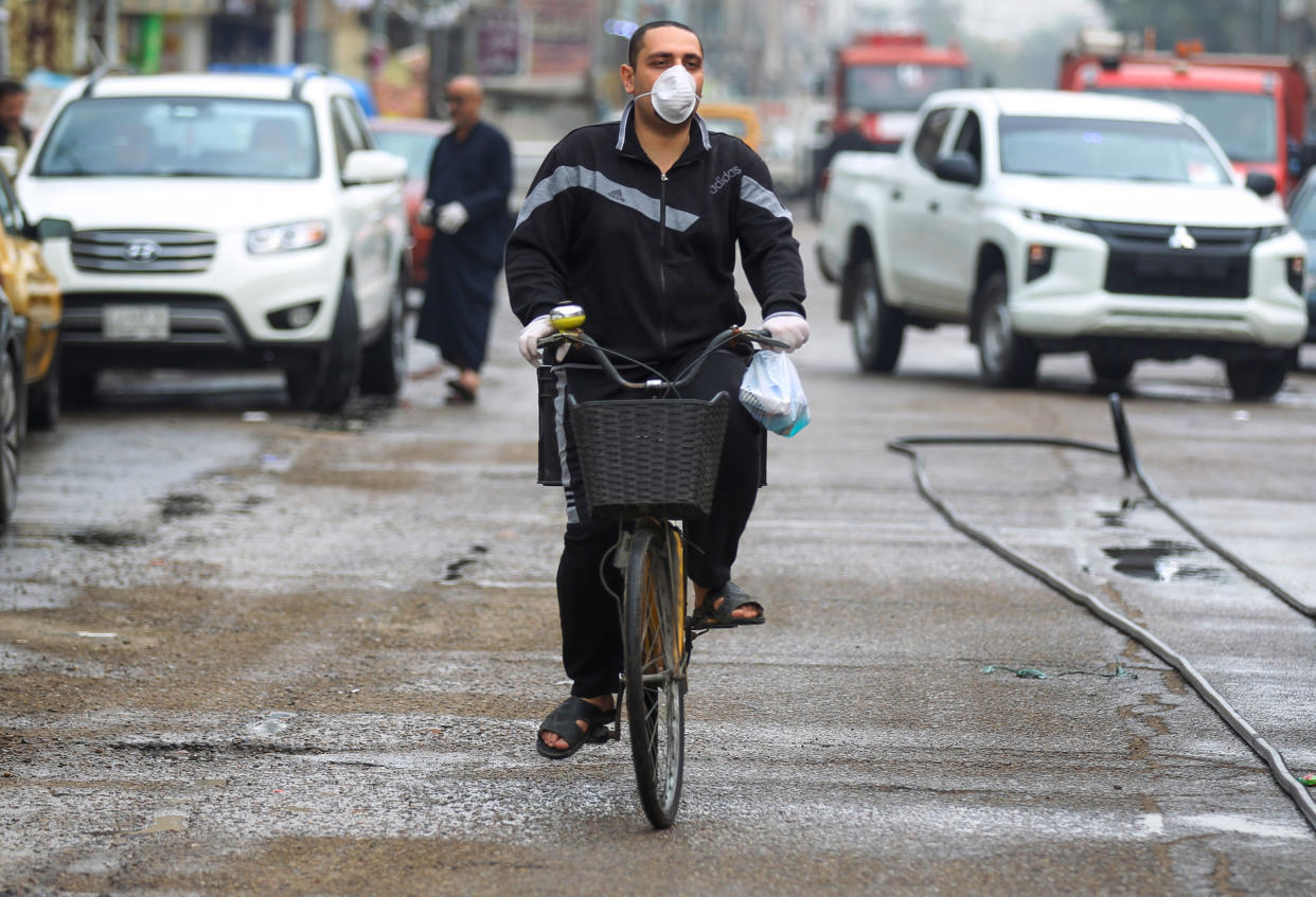 An Iraqi man, wearing a protective mask, rides a bicycle down street in the capital Baghdad on March 16, 2020 amidst efforts against the spread of COVID-19 coronavirus disease. (Photo by AHMAD AL-RUBAYE / AFP) (Photo by AHMAD AL-RUBAYE/AFP via Getty Images)