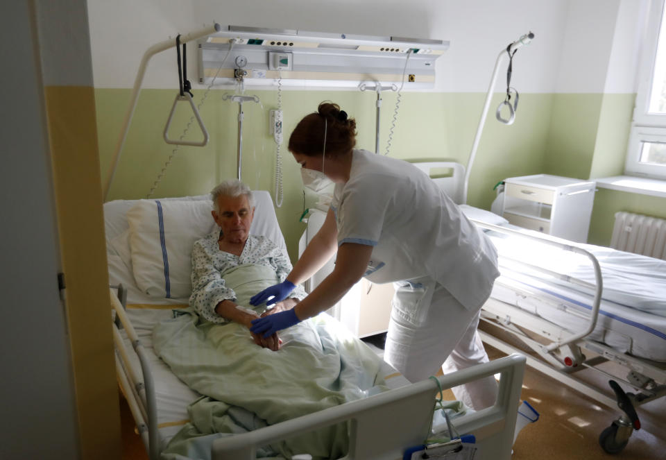 Karolina Repikova, a 22-year-old student at a vocational school, tends to a patient at a hospital in Kyjov, Czech Republic, Thursday, Oct. 22, 2020. With cases surging in central Europe, some countries are calling in soldiers, firefighters, students and retired doctors to help shore up buckling health care systems. (AP Photo/Petr David Josek)