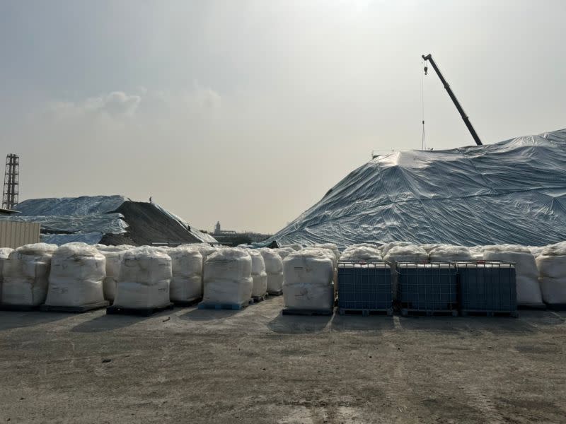 ▲現場堆置污染土方用帆布（藍白色）覆蓋，後面覆蓋防塵網，太空包為生物製劑，添加在執行污染土方生物復育使用。（圖／高雄市環保局提供）