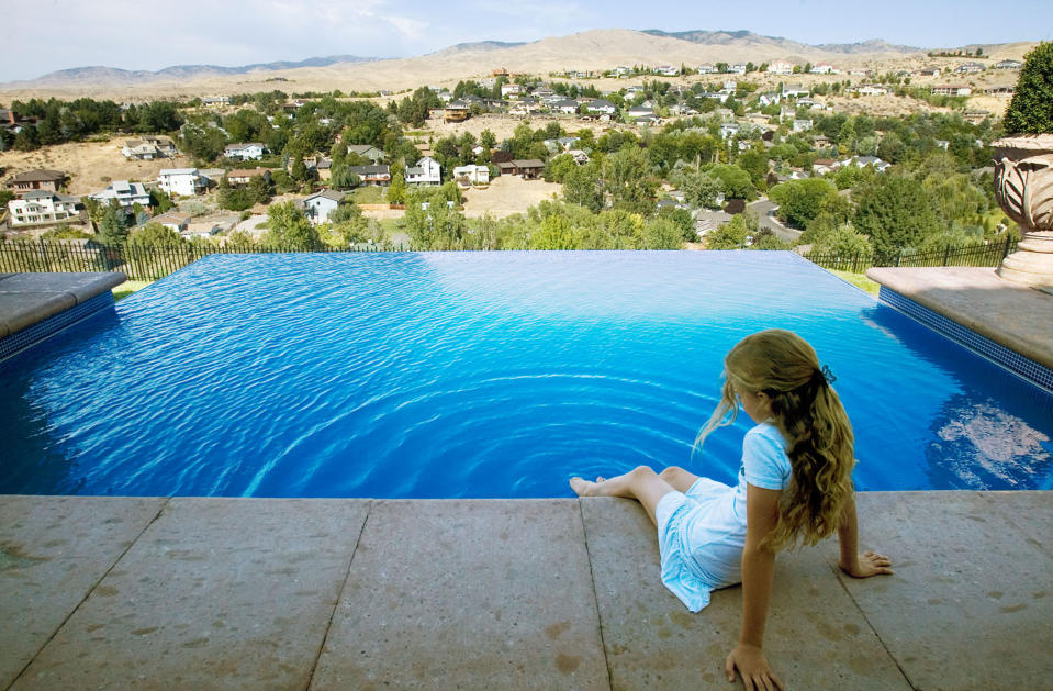 Francesca Williams, 11, dips her foot in the pool. The infinity edge makes it appear as if the water is magically contained. Homeowner and builder Cris hand-tiled the pool over the winter.  (Photo by Darin Oswald/Idaho Statesman/Tribune News Service via Getty Images)