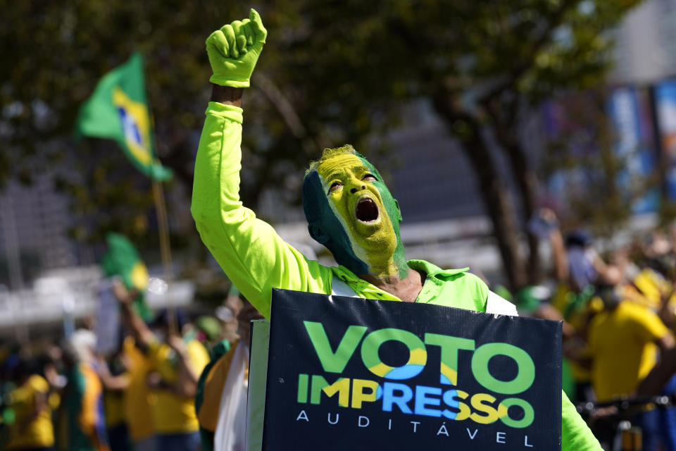 A supporter of Brazil's President Jair Bolsonaro carries a sign that reads in Portuguese "Printed and auditable vote," during a pro-Bolsonaro rally at the Esplanade of Ministries, in Brasilia, Brazil, Sunday, Aug. 1, 2021. Political backers of President Bolsonaro have called for nationwide rallies to express their support for the embattled leader and his call for adding printouts to the electronic voting system. (AP Photo/Eraldo Peres)