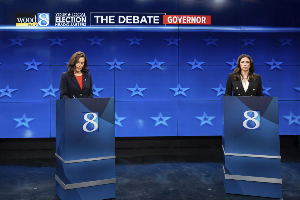 Gretchen Whitmer and Tudor Dixon stand behind podiums on a TV set before a debate.