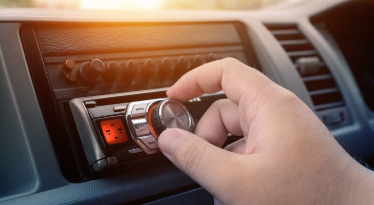 A close-up shot of a hand adjusting an audio knob in a car dashboard.