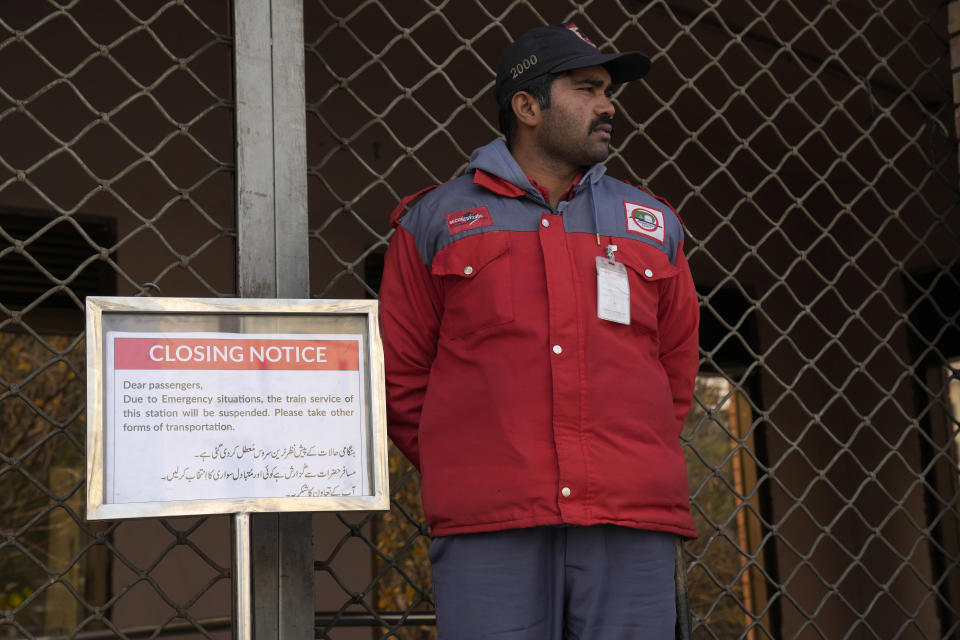 A worker of the Orange Line metro train stands next to a closing notice board at a station following a power breakdown across the country, in Lahore, Pakistan, Monday, Jan. 23, 2023. Much of Pakistan was left without power for several hours on Monday morning as an energy-saving measure by the government backfired. The outage spread panic and raised questions about the cash-strapped government’s handling of the crisis. (AP Photo/K.M. Chaudary)