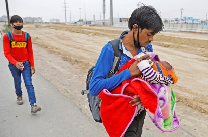 A migrant worker feeds his newborn baby as he walks on a highway looking out for a transport to return to his village, after India ordered a 21-day nationwide lockdown to limit the spreading of coronavirus disease (COVID-19), in Ghaziabad