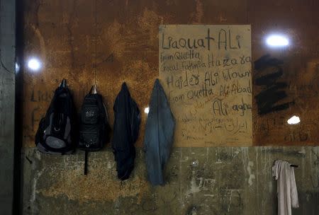 The belongings of Afghan immigrants hang on a graffitied wall inside a wood factory across the street from a ferry terminal in the western Greek town of Patras April 28, 2015. REUTERS/Yannis Behrakis