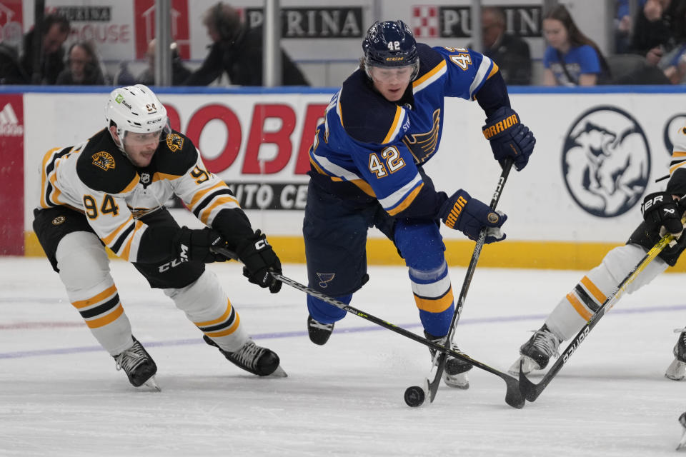 St. Louis Blues' Kasperi Kapanen (42) and Boston Bruins' Jakub Lauko (94) battle for a loose puck during the second period of an NHL hockey game Sunday, April 2, 2023, in St. Louis. (AP Photo/Jeff Roberson)