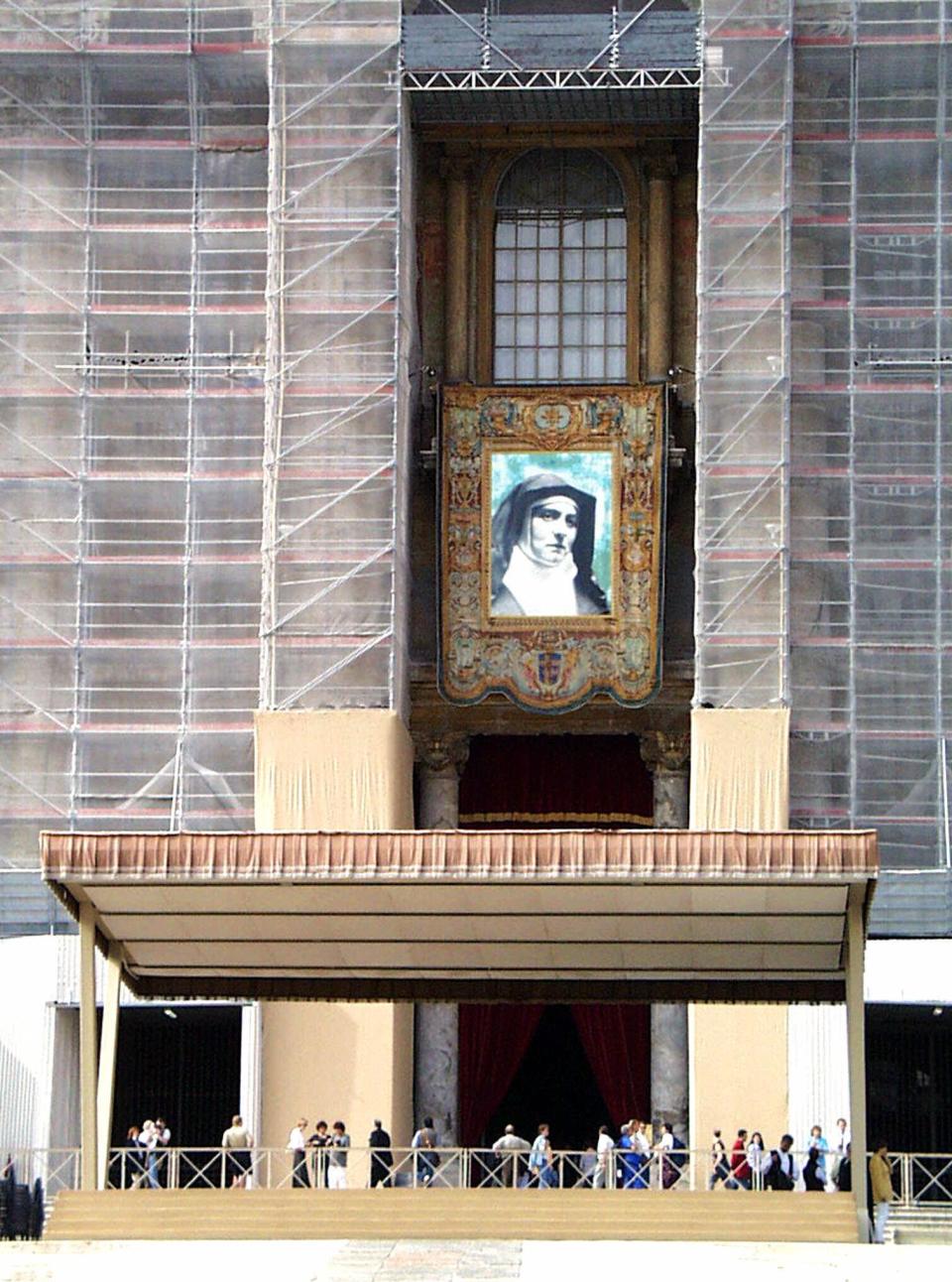 FILE - Edith Stein is seen on a tapestry hanging on the facade St. Peter's Basilica, currently undergoing restoration, at the Vatican, Oct. 10, 1998. Cardinal Michael Czerny marked the 80th anniversary of the gas chamber killing of the Jewish-born Catholic convert Edith Stein on Tuesday Aug. 9, 2022, by celebrating a Mass at the former Auschwitz death camp and telling the story of his own family’s Jewish origins and their fate with the Nazis. (AP Photo/Corrado Giambalvo, File)