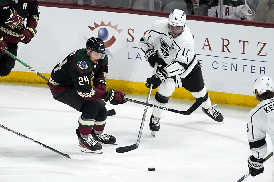 Arizona Coyotes defenseman Matt Dumba (24) and Los Angeles Kings center Anze Kopitar (11) battle for the puck during the third period of an NHL hockey game, Monday, Nov. 20, 2023, in Tempe, Ariz. (AP Photo/Matt York)