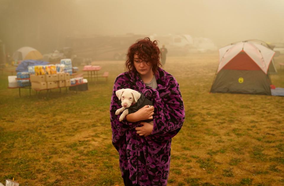 Shayanne Summers holds her dog Toph while wrapped in a blanket after several days of staying in a tent at an evacuation center at the Milwaukie-Portland Elks Lodge, on Sept. 13, 2020, in Oak Grove, Ore.