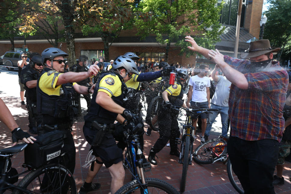 FILE - In this June 29, 2019, file photo, after a confrontation between authorities and protesters, police use pepper spray as multiple groups, including Rose City Antifa, the Proud Boys and others protest in downtown Portland, Ore. Portland police are mobilizing in hopes of avoiding clashes between out-of-state hate groups planning a rally Saturday, Aug. 17, 2019, and homegrown anti-fascists who say they’ll come out to oppose them. (Dave Killen/The Oregonian via AP, File)