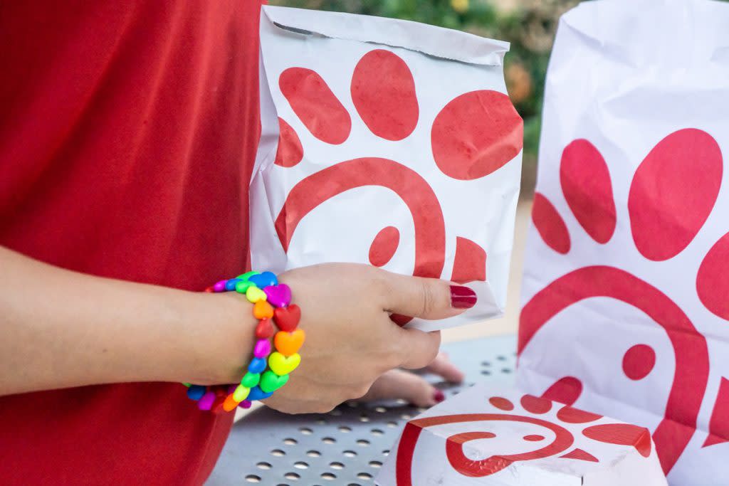 A person holds bags and boxes containing Chick-fil-A food. 