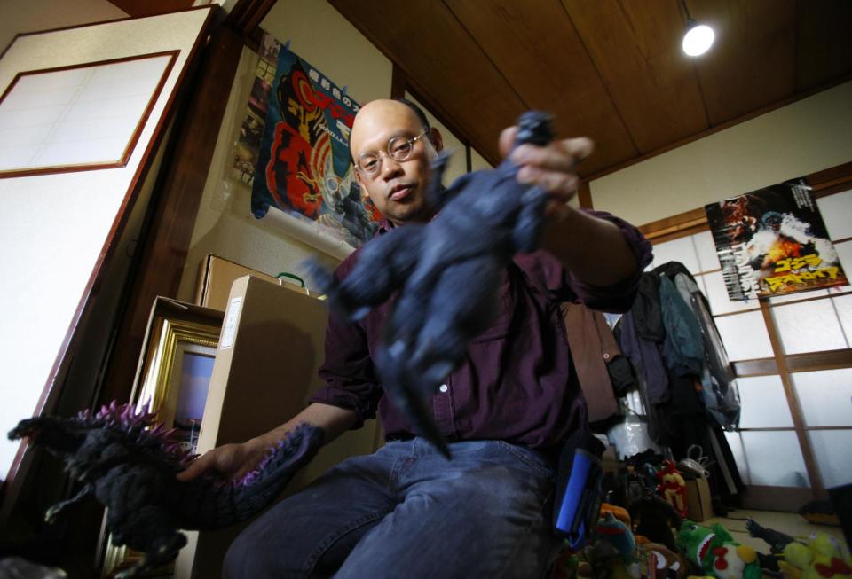 In this Thursday, May 1, 2014 photo, Kazuya Haraguchi, 45, a technician for film reel, picks up a figure of original Godzilla, right, and another Godzilla that appeared in later movie at his apartment in Tokyo. Haraguchi says Hollywood already botched it once with the 1998 remake, directed by Roland Emmerich. And almost everything about the new Godzilla is wrong again, from head to toe - how its arms are limp at its sides, how the scales on its back are too regular, even the shape of its head. (AP Photo/Junji Kurokawa)