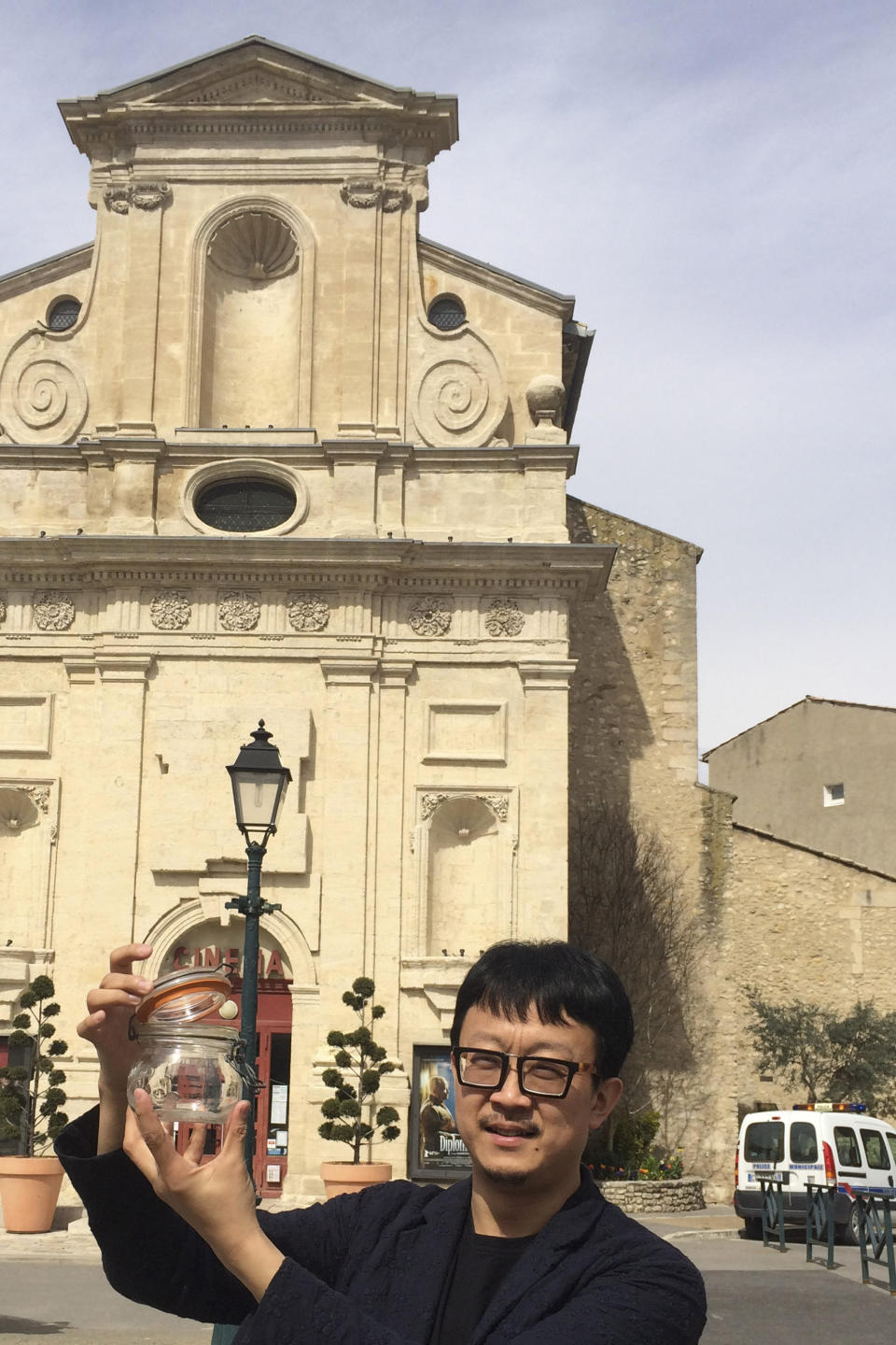 In this photo taken on March 29, 2014, Beijing artist Liang Kegang collects fresh air in the commune of Forcalquier in Provence, France. The jar of air is a piece of conceptual art to protest his home city's choking pollution. It has fetched $860 in a small auction. (AP Photo/Liang Kegang)