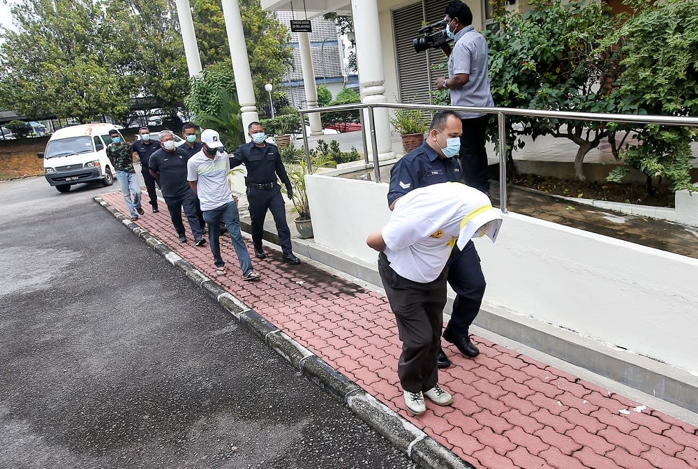 The three men who defied the movement control order by playing golf are led in handcuffs to the Magistrate Court in Batu Gajah April 17, 2020. — Picture by Farhan Najib