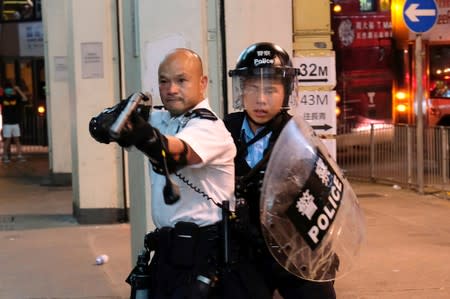 FILE PHOTO: A police officer points a gun towards anti-extradition bill protesters who surrounded a police station where detained protesters are being held during clashes in Hong Kong