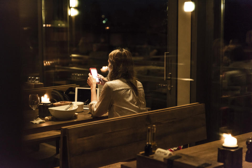 Woman using cell phone at dining table