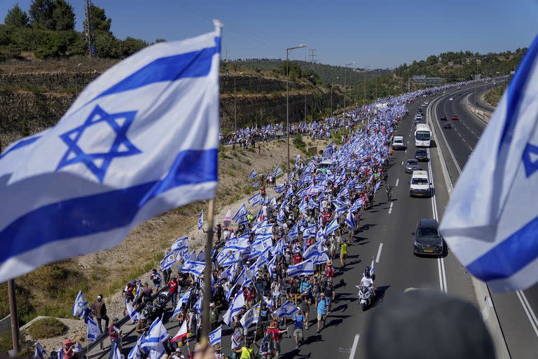 Miles de israelíes marchan por una autopista hacia Jerusalén en protesta por los planes del gobierno del primer ministro, Benjamin Netanyahu, de reformar el sistema judicial, cerca de  Abu Gosh, Israel, el sábado 22 de julio de 2023.  (AP Foto/Ohad Zwigenberg)