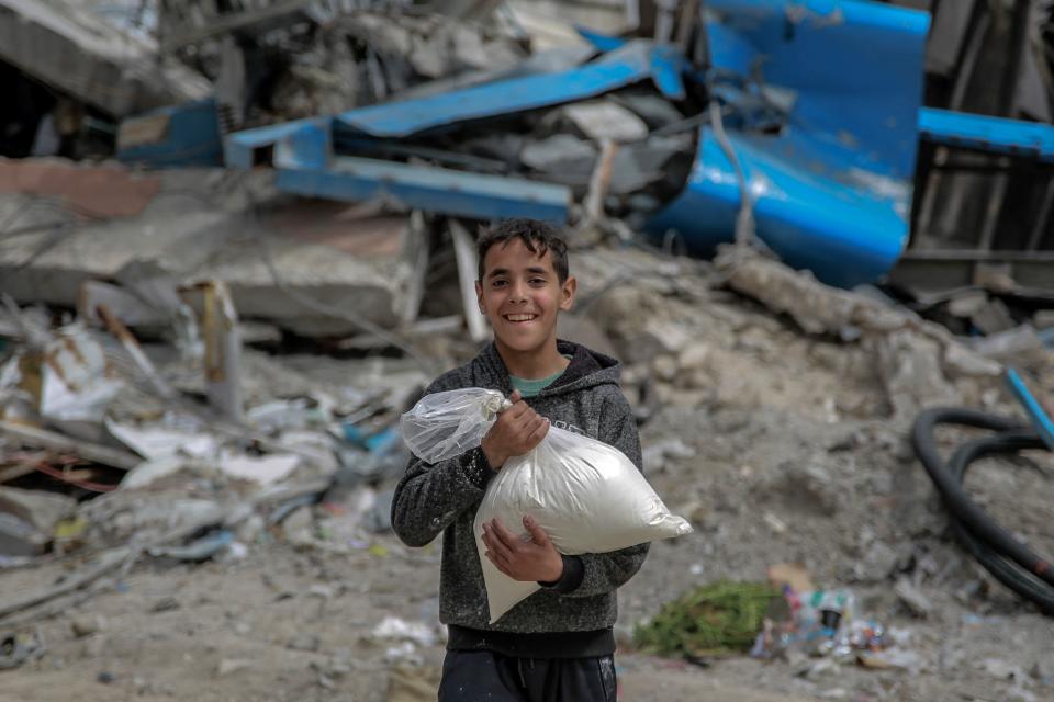 A boy carries a bag of flour after humanitarian aid was distributed in Gaza City on March 17, 2024.