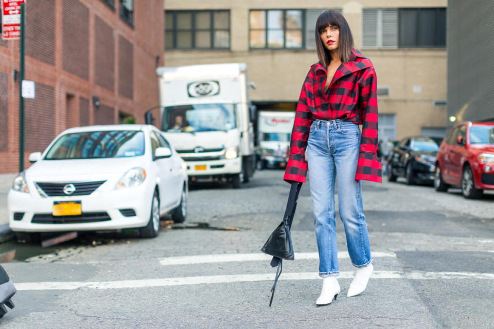 A black leather triangle bag looks cool against a bold top and graphic white boots at New York Fashion Week.