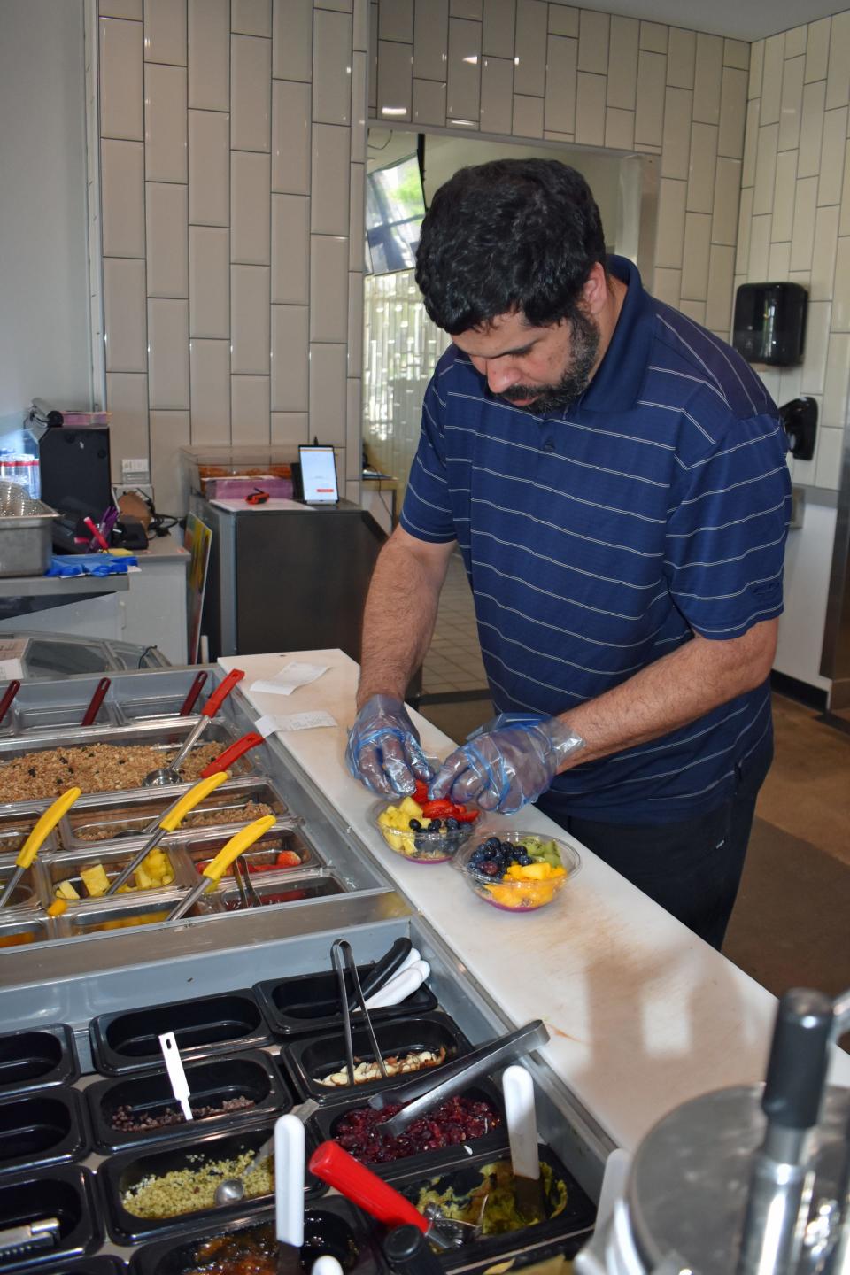 Irangel Gonzalez creates two customized fruit bowls at Frutta Bowls in Ankeny, which he owns with his wife Julie. "They're like eating a rainbow," she said.