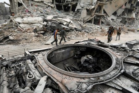 Syrian army soldiers walk past a damaged military vehicle in al-Hajar al-Aswad, Syria May 22, 2018. REUTERS/Omar Sanadiki