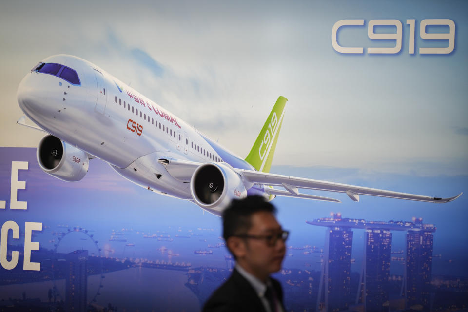 A visitor walks in front of a poster of China's Comac C919 aircraft during the first day of Singapore Airshow in Singapore, Tuesday, Feb. 20, 2024. The Singapore Airshow, Asia's largest, kicked off Tuesday with an array of aerial displays including some by China's COMAC C919 narrow-body airliner.(AP Photo/Vincent Thian)