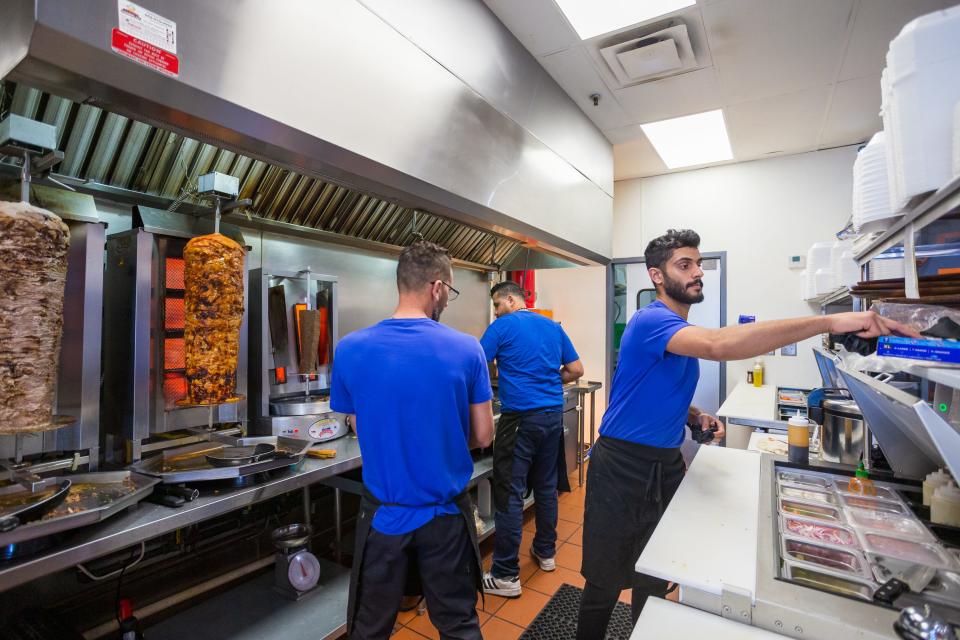 Ali Al Zubaidi, left, Mohammed Al Jaburi, middle, and Yousif Al Zubaidi prepare food in the kitchen at Supreme Shawarma in Chandler on Feb. 17, 2022.