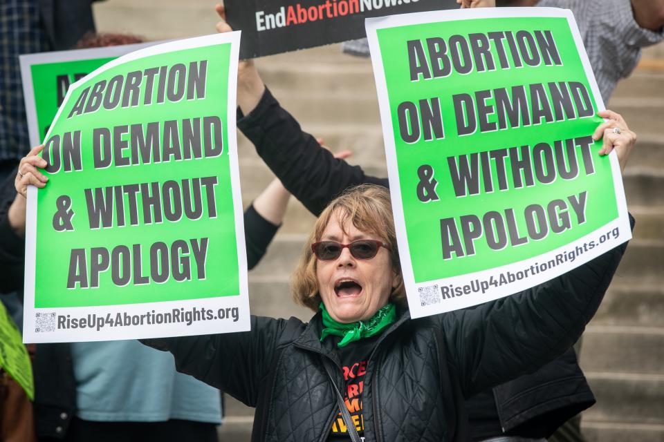 Jay Becker holds signs as she protests Kentucky's new abortion law outside Louisville Metro Hall on April 21, 2022.