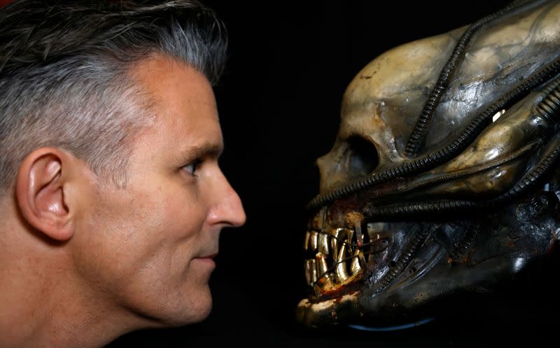 Stephen Lane, CEO of Prop Store, poses for a photograph with a special effects mechanical head from the film Alien at a preview of a movie and TV memorabilia auction in Rickmansworth