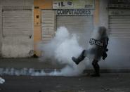 A riot police officer kicks a tear gas canister during clashes with protesters after a man, who was detained for violating social distancing rules, died from being repeatedly shocked with a stun gun by officers, according to authorities, in Bogota