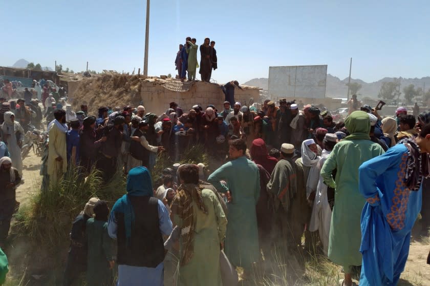 Taliban fighters and Afghans gather around the body of a member of the security forces who was killed, inside the city of Farah, capital of Farah province, southwest Afghanistan, Wednesday, Aug. 11, 2021. Afghan officials say three more provincial capitals have fallen to the Taliban, putting nine out of the country's 34 in the insurgents' hands amid the U.S. withdrawal. The officials told The Associated Press on Wednesday that the capitals of Badakhshan, Baghlan and Farah provinces all fell. (AP Photo/Mohammad Asif Khan)