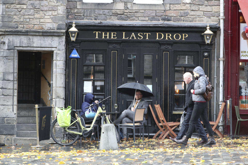 People drink outside the Last Drop pub as temporary restrictions announced by First Minister Nicola Sturgeon to help curb the spread of coronavirus will come into effect from 6pm, in Edinburgh, Friday, Oct. 9, 2020. (Andrew Milligan/PA via AP)