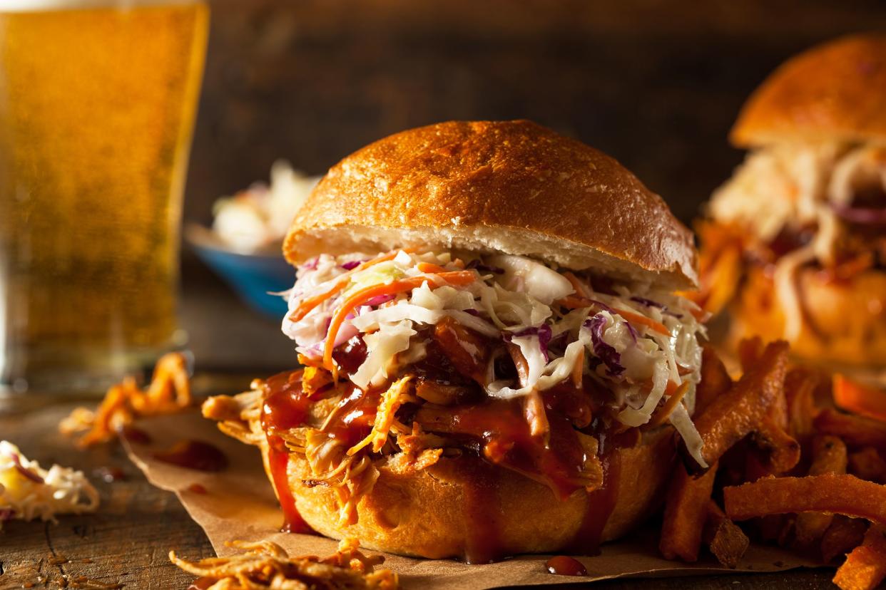 Slow cooker BBQ chicken in a bun on a rustic wooden table with a blurred background