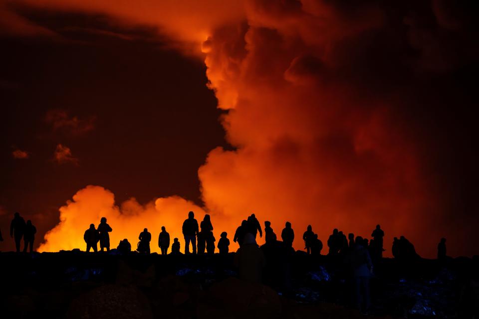 Spectators watch plumes of smoke from volcanic activity between Hagafell and Stóri-Skógfell, Iceland, Saturday, March 16, 2024.