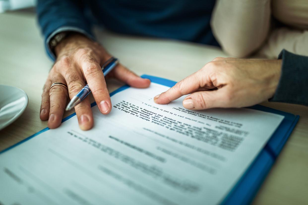 finger pointing to life insurance policy for senior's hand to sign