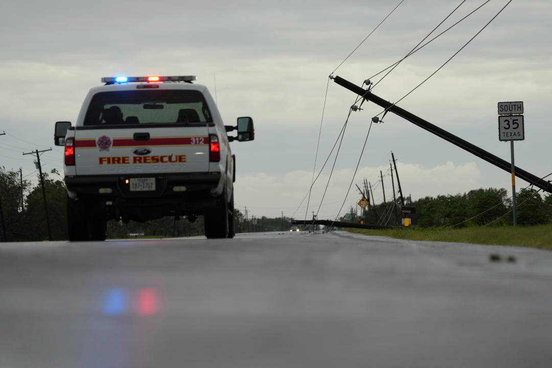 A Fire Rescue emergency vehicle drives on a deserted highway, near a downed power line.