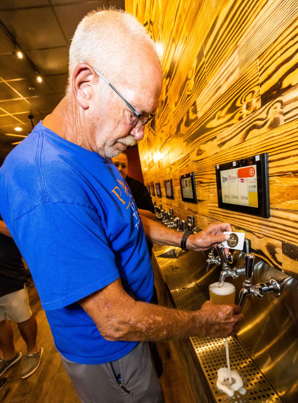 Robert Robinson pours himself a beer at the Crave Hot Dogs & BBQ soft opening on Aug. 4.