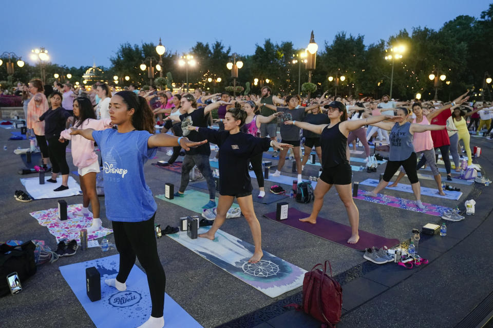 Nearly 2,000 Cast Members practice sunrise yoga celebrating International Yoga Day in front of Cinderella Castle at the Magic Kingdom Park at Walt Disney World Tuesday, June 21, 2022, in Lake Buena Vista, Fla. (AP Photo/John Raoux)