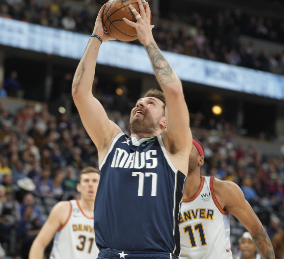 Dallas Mavericks guard Luka Doncic, front, drives to the rim past Denver Nuggets forward Bruce Brown in the first half of an NBA basketball game Wednesday, Feb. 15, 2023, in Denver. (AP Photo/David Zalubowski)