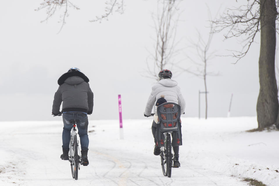 FILE - People bike next to the St. Lawrence River during snowy conditions in Montreal, Saturday, Jan. 1, 2022. Montreal has been known for decades as a global innovator in urban biking and the first city in North America to develop an extensive network of physically separated on-street bicycle lanes. (Graham Hughes /The Canadian Press via AP, File)
