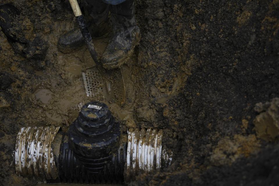 Jason Pierson digs while installing drainage tile in an agricultural field, Tuesday, April 9, 2024, in Sabina, Ohio. These tiles are large perforated plastic pipes about 3 feet (1 meter) below the soil that collect water and carry it away, usually to a canal between fields. (AP Photo/Joshua A. Bickel)