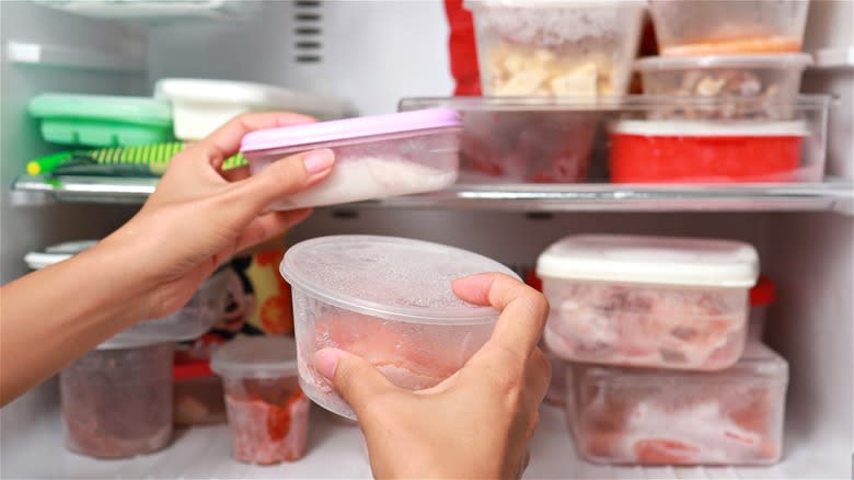 Hands holding frozen food containers 