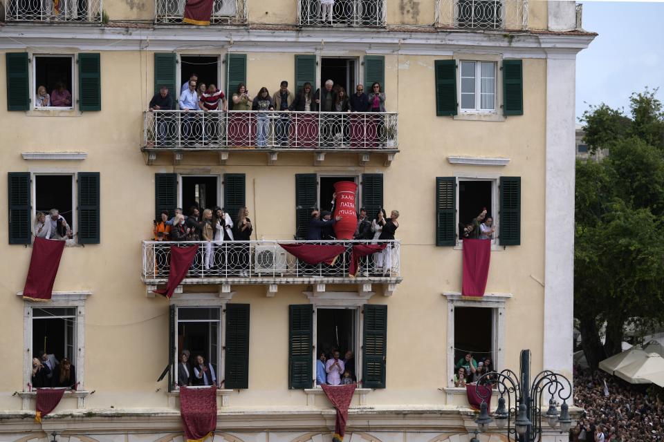 People prepare to throw a huge clay jar from a balcony during the custom called "botides" on the Ionian Sea island of Corfu, northwestern Greece, Saturday, April 23, 2022. For the first time in three years, Greeks were able to celebrate Easter without the restrictions made necessary by the coronavirus pandemic. (AP Photo/Thanassis Stavrakis)
