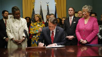Virginia Gov. Glenn Youngkin, center, signs executive orders in the Governors conference room as Lt. Gov. Winsome Earle-Sears, left, Suzanne Youngkin, Second from left, Attorney General Jason Miyares, second from right, and Secretary of the Commonwealth, Kay Cole James, right, look on at the Capitol Saturday Jan. 15, 2022, in Richmond, Va. (AP Photo/Steve Helber)